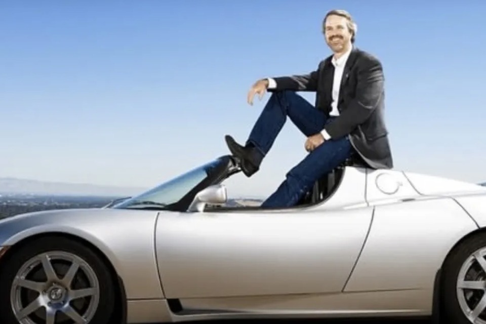 Martin Eberhard seated on a silver Tesla Roadster
