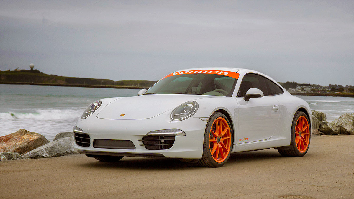 White Vonnen Porsche 911 with orange wheels beside the coast